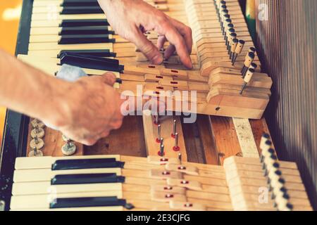 Setting up an old piano. The master repairs an old piano. Deep cleaning the piano. Hands of professional worker repairing and tuning an old piano Stock Photo