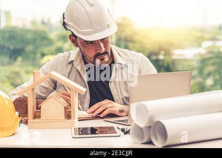 Young man architect or engineer working at desk with designer equipment to make interior design at workplace. Real estate business and civil Stock Photo