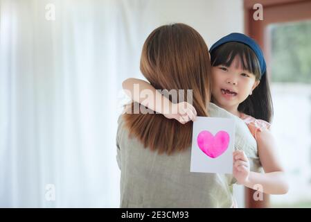 https://l450v.alamy.com/450v/2e3cm93/asian-mother-hug-her-cute-daughter-that-give-handmade-greeting-card-with-colourful-heart-symbol-to-surprising-her-at-home-2e3cm93.jpg