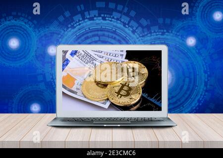 Smart Computer with Bitcoins on investment money moving graph on screen on wood table with futuristic technology background. Stock Photo