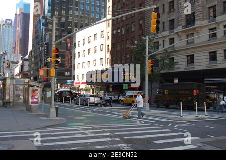 New York USA traffic lights man crossing the road with hat hotel hotels taxi parked yellow cab signs markings on road skyscrapers skyscraper  UPS van Stock Photo