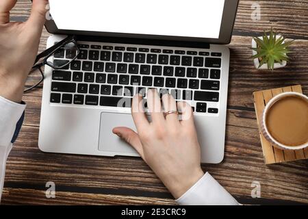 Top view of hipster wooden workspace, office table desk. Flat lay view of man hands working on a laptop. Office work. Business meeting. Coffee break. Stock Photo