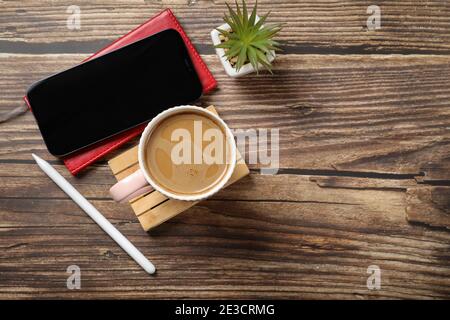 Flat lay view of a red notebook, smartphone, pen on a wooden background. Top view of modern office workplace. Stock Photo