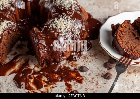 Angled side view of a gourmet round chocolate cake with coconut shreds on icing. Two slices were removed and placed on white porcelain plate with a me Stock Photo