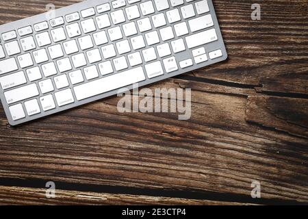 Top view of a white keyboard on a wooden table. Copy space.  Stock Photo