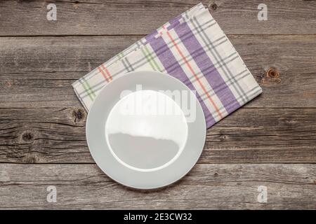Empty white plate and kitchen napkin on an old wooden table. View from above Stock Photo