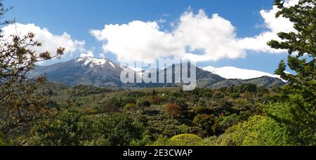 Picturesque view of the mountains in Crete, Greece framed by foliage in the Spring with snow on the peaks
