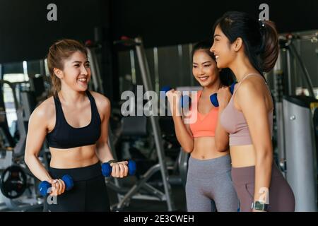 Happy young multiracial team of female athletes in sportswear training together with dumbbells in fitness club Stock Photo