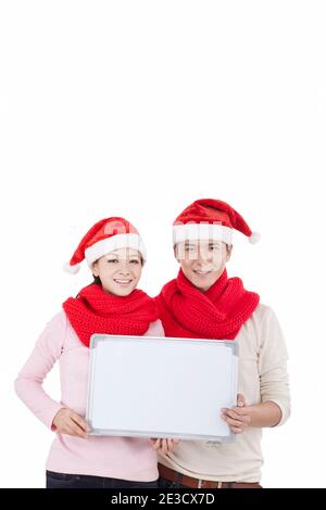 Portrait of young couple wearing Santa hats,holding whiteboard high quality photo Stock Photo