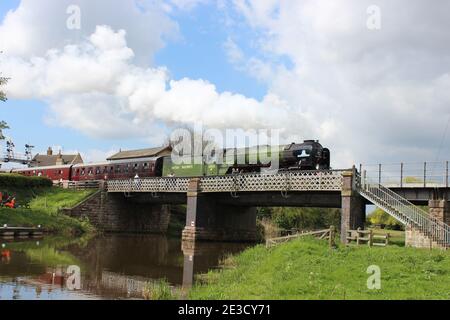 Peppercorn A1 class 60163 Tornado departs from Wansford station at the Nene Valley Railway and chuffs over the river bridge. Stock Photo