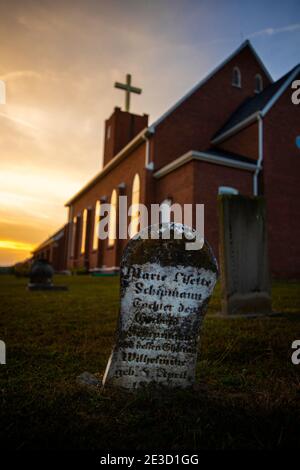 An old headstone in the German cemetery at Sauers Lutheran Church in Jackson County, IN.  Taken during the sunset. Stock Photo