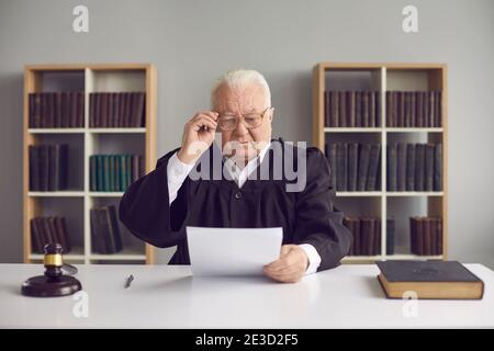 Senior man professional judge learning details of case on paper during court Stock Photo