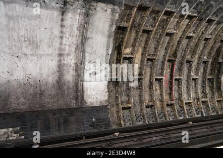 London, United Kingdom - February 02, 2019: Old dirty wall in tube train tunnel, missing London Underground logo on concrete Stock Photo