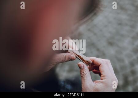 Close up of man making cigarette while rolling with dried smoking tobacco and white paper Stock Photo