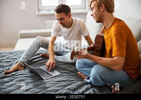 Beautiful gay couple using modern laptop at home Stock Photo