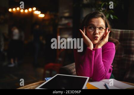 Waist up of beautiful woman wearing glasses and working with tablet in cafe while having fun Stock Photo