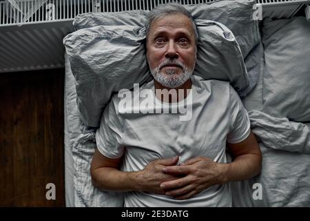 middle-aged man lying down in bed on pillow, having insomnia sleeping disorder. alone at home Stock Photo