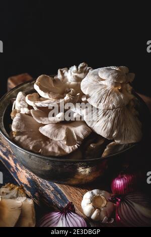 Oyster mushrooms in an old pot with vegetables on dark background. Close-up. Stock Photo