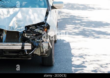 Injured drunk man driving wrecked Destroyed car. Car crash traffic accident on city road. Smashed broken front auto headlight, dented hood without Stock Photo