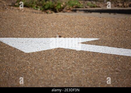 White arrow on an asphalt road, pointing away Stock Photo