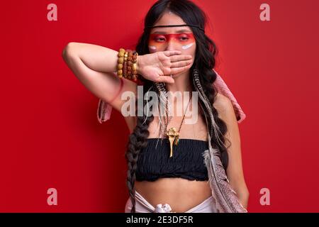 indian woman keep silence, isolated on red background, stand closing mouth, wearing top. portrait