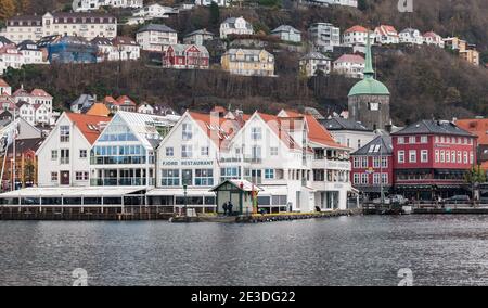 Bergen, Norway - November 17, 2017: Coastal cityscape of Bergen harbor. Fjord restaurant facade. Ordinary people are on the street Stock Photo
