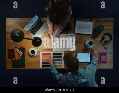 Top view of architects working on computer at desk with paperwork in office. Stock Photo