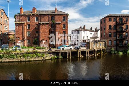 A fisherman sits on an old quayside on the River Aire in a partially regenerated post-industrial area of central Leeds. Stock Photo