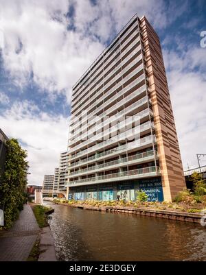 Modern high rise apartment buildings stand on redeveloped industrial land beside the Bridgewater Canal in Manchester. Stock Photo