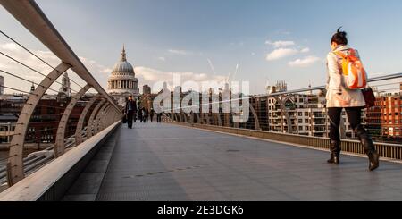 London, England, UK - April 20, 2010: Pedestrians walk across London's Millennium Bridge, with St Paul's Cathedral and offices of the Square Mile beyo Stock Photo
