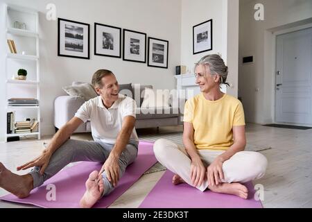 Fit active mature wife and senior husband having fun exercising at home. Stock Photo