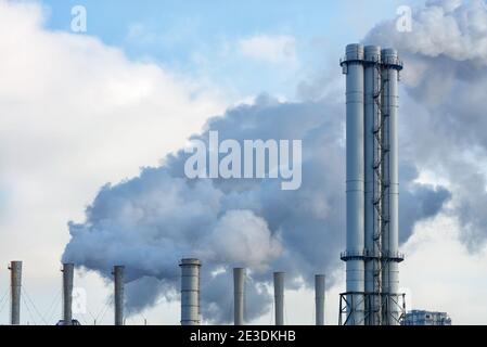 Smoking chimneys from the city thermal station against the background of the winter sky during the heating season, copy space. Stock Photo