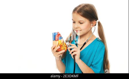 Cute little girl listens to the heart using a stethoscope. Child playing doctor cardiologist, future profession. White background Stock Photo
