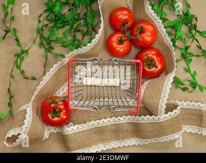 Vegan written on wooden cubes surrounded with vegetables in shoppin basket top view with craft paper background, Vegan, Healthy food, Vegetarian Stock Photo