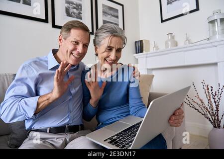 Happy senior couple greeting family making online video call on laptop.