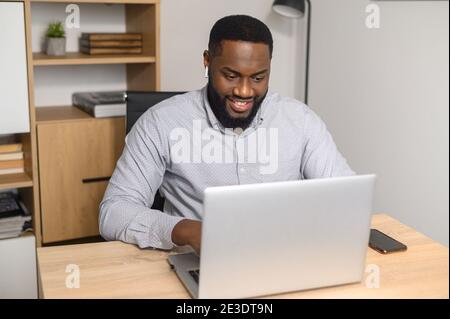 Excited AfricanAmerican male worker writing email Stock Photo