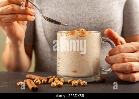 Woman eating a viscose malted barley, wheat beverage served in a cup with roasted chickpeas (leblebi) and cinnamon powder. This seasonal drink popular Stock Photo