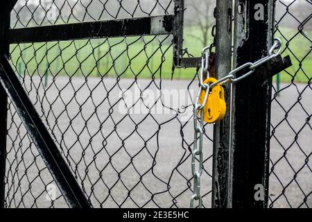 Playing courts, tennis and basketball, locked with yellow padlock and chain during the covid19 lockdown, London. Stock Photo