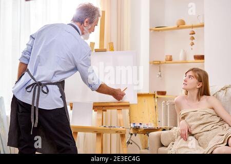 female posing for portrait, professional painter drawing portrait of young lady in studio Stock Photo