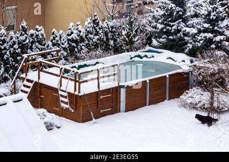 Wooden structure outdoor garden swimming pool covered with snow and ice in winter Stock Photo