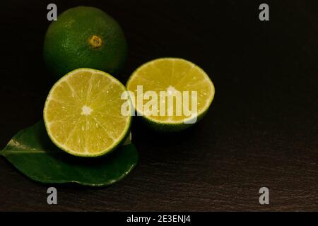 Pieces of lime and whole lime on a black background Stock Photo