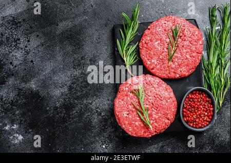 Patty of minced meat for burger. Black background. Top view. Copy space Stock Photo