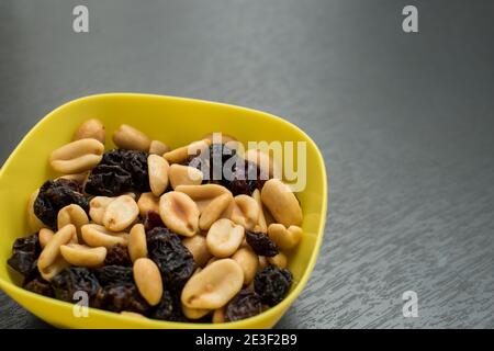 Some peanuts, raisins and nuts in a pot on a dark wooden table Stock Photo