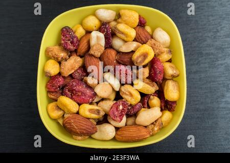 Some peanuts, raisins and nuts in a pot on a dark wooden table Stock Photo