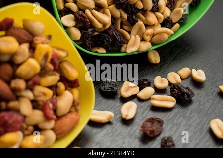 Some peanuts, raisins and nuts in a pot on a dark wooden table Stock Photo