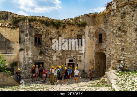 Craco, Basilicata, Italy, August 2020 - Tourists in a guided tour visiting Craco, an abandoned ghost town in the province of Matera Stock Photo