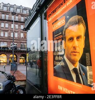 Strasbourg, France - Jan 7, 2021: People with anti-Covid-19 masks on French city Street with portrait of French President Emmanuel Macron on the cover of L'Express interview advertising at press kiosk Stock Photo