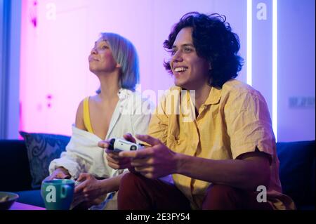 Photo of young couple playing video games at home at night Stock Photo