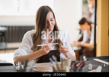 Young women learning to sculpt with a clay during a lesson at workshop in art studio. Stock Photo