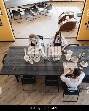 Young women learning to sculpt with a clay during a lesson at workshop in art studio. Stock Photo